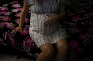 Una mujer embarazada se sienta en una cama sosteniendo su vientre. (photo por: CALLAGHAN O'HARE/REUTERS)
